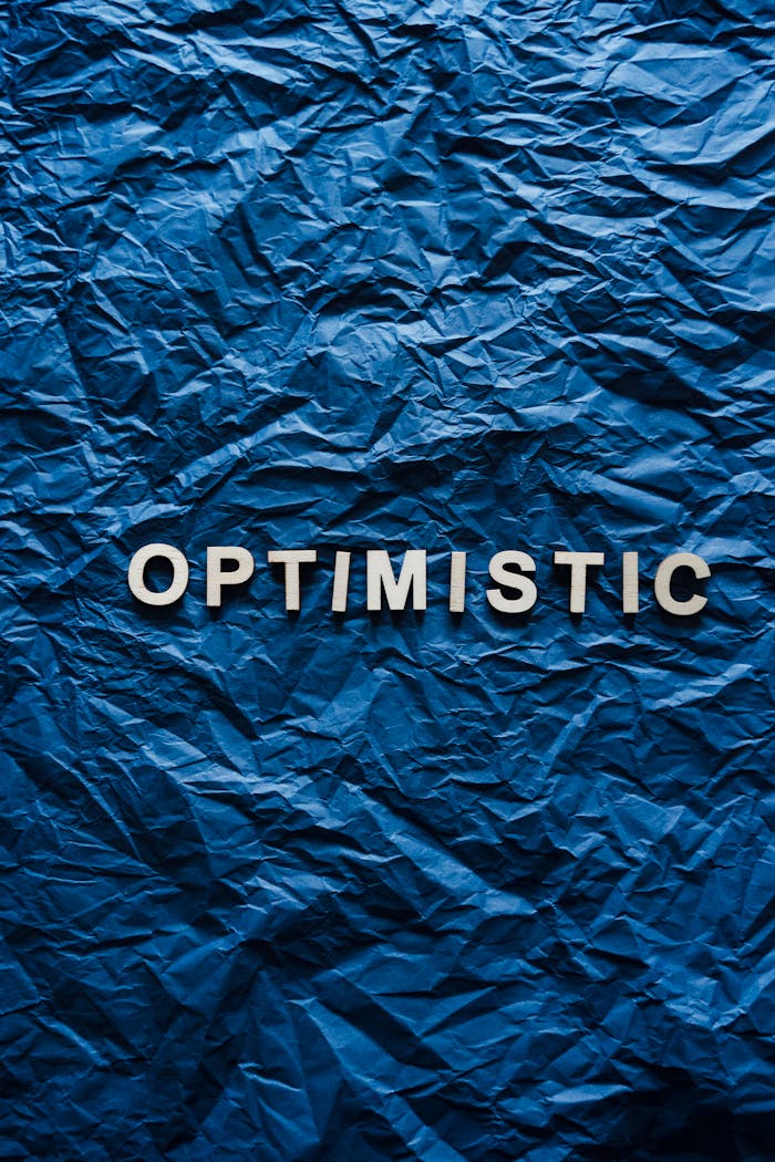 Close-up of the word Optimistic on crumpled blue paper texture.